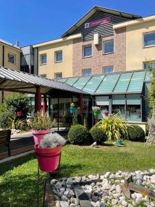 a building with potted plants in front of a building at Aiden by Best Western Paris Roissy CDG in Roissy-en-France