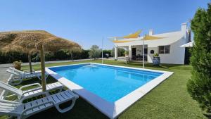 una piscina con dos sillas y una sombrilla en Casa Rural The Hope, en La Puebla de Cazalla