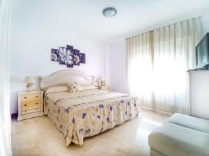 a white bedroom with a bed and a window at Banana Beach in Marbella
