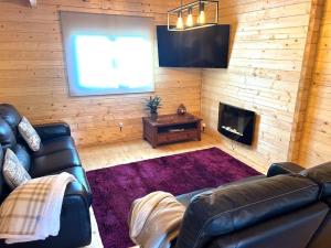 a living room with a leather couch and a television at Casa do Baloiço do Pitagudo in Maceira