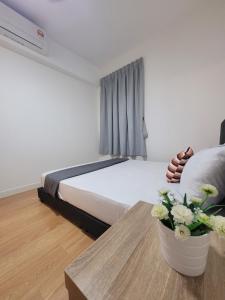 a bedroom with a bed and a table with flowers on it at Edumetro Homes in Subang Jaya