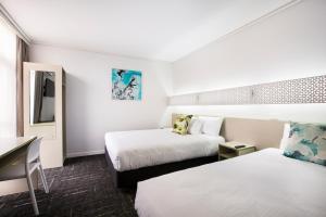 a bedroom with a bed, a desk, and a painting on the wall at Nightcap at Sandringham Hotel in Sandringham