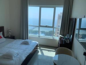 1 dormitorio con cama y ventana grande en Family rooms with beach view en Ajman 