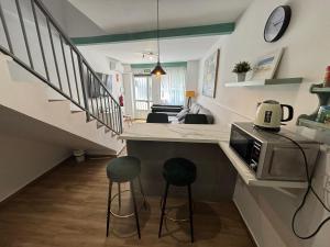 una cucina con due sgabelli e un bancone con forno a microonde di Loft Picasso Badajoz en Casco Histórico a Badajoz