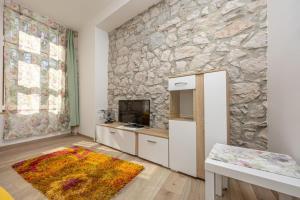 a living room with a stone wall and a television at Apartmani Leo centar in Crikvenica