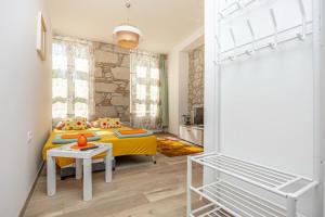 a bedroom with a yellow bed and a table at Apartmani Leo centar in Crikvenica