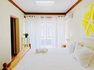 1 dormitorio con 1 cama blanca grande y 2 toallas en Benagil Beach House - Yasmin en Lagoa