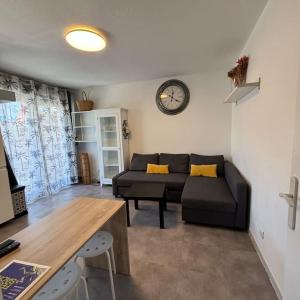 a living room with a couch and a clock on the wall at appartement terrasse et piscine in Montpellier