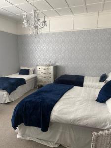 a bedroom with two beds and a chandelier at Fox House Thirdpart Farm in Beith