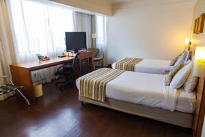 a hotel room with two beds and a desk and a computer at Quality Porto Alegre in Porto Alegre