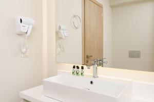 a white bathroom with a sink and a mirror at Gallery Central Piraeus Port in Piraeus