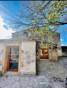 a stone house with two windows and a tree at Masía entre viñedos y mar in Saiforas