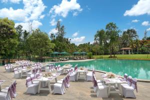 a dining area with tables and chairs next to a pool at Big Banyan Vineyard & Resort in Bangalore