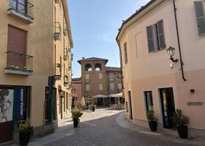 an alley with buildings and a clock tower in the distance at Casa Mandelli in Alba