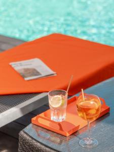 una bebida en una bandeja de naranja junto a una piscina en Holiday Inn Toulouse Airport, an IHG Hotel en Blagnac