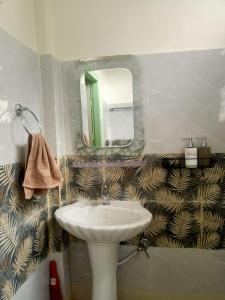 ein Bad mit einem Waschbecken und einem Spiegel in der Unterkunft Axom Aura in Tezpur