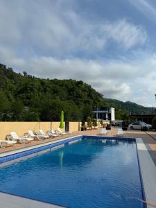 a swimming pool with lounge chairs and a building at Villa Edelweiss in Batumi