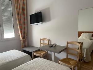 um quarto com duas camas e uma mesa com uma televisão na parede em Vehí em Cadaqués