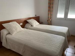 um quarto com 2 camas com lençóis brancos e uma janela em Vehí em Cadaqués