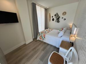 ein Hotelzimmer mit einem Bett und einem Flachbild-TV in der Unterkunft La Puerta de Nerja BOUTIQUE - Adults Recommended in Nerja