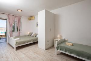 ein weißes Schlafzimmer mit zwei Betten und einem Fenster in der Unterkunft XXL Apartment - Private Pool in Omiš