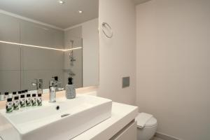 a white bathroom with a sink and a toilet at Gallery Central Piraeus Port in Piraeus