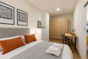 Schlafzimmer mit einem Bett mit orangefarbenen Kissen und einem Schreibtisch in der Unterkunft Apartamento Boutique a estrenar in Sevilla