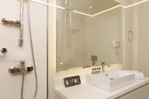 a white bathroom with a sink and a shower at Gallery Central Piraeus Port in Piraeus