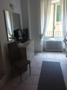 Habitación con silla, TV y ventana en B&B e Residence Abbazia di Piona en Colico