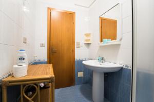 Un baño con lavabo y puerta de madera. en Casa Penelope, en Favignana