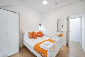 1 dormitorio blanco con 1 cama grande con almohadas de color naranja en The Cutesy - Fitzrovia - by Frankie Says, en Londres