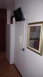 a room with a television on a wall with a refrigerator at A casa SCALILLA in Palermo