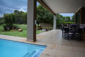 a swimming pool with chairs and a table on a patio at Kingfisher on Vaal, Parys in Parys