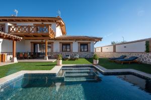 a villa with a swimming pool in front of a house at Arandas Village in Navahermosa