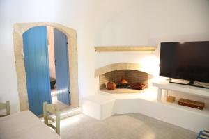 a living room with a tv and a fireplace at Traditional house in Mitata next to the canyon! in Kýthira