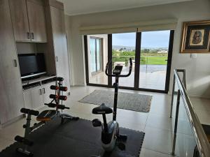 a gym with cardio equipment in a room with a large window at Langebaan Golf Estate - Signature Hole 24hrs power in Langebaan