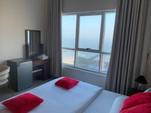 a bedroom with a bed with red pillows and a window at Family rooms with beach view in Ajman 