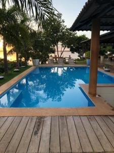 einen großen blauen Pool mit Holzterrasse in der Unterkunft Chácara Por do Sol Beira Lago in Palmas