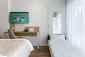 - une chambre avec 2 lits et une télévision murale dans l'établissement Hôtel Restaurant La Forestière, à Biscarrosse-Plage