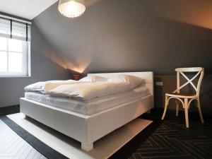a bedroom with a white bed and a chair at Jolle Ferienhaus in Groß Schwansee