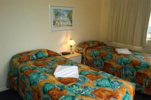 um quarto de hotel com duas camas e uma mesa com um candeeiro em Diamond Sands Resort em Gold Coast