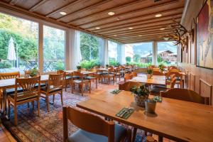 un ristorante con tavoli, sedie e ampie finestre di Hotel des Alpes a Flims