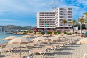 a beach with chairs and umbrellas and a building at NYX Hotel Ibiza by Leonardo Hotels-Adults Only in San Antonio Bay
