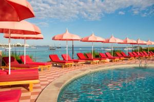 uma piscina com cadeiras vermelhas e guarda-sóis em NYX Hotel Ibiza by Leonardo Hotels-Adults Only em San Antonio Bay