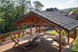 a wooden pavilion with a hammock and a chair on a deck at Apartamenty Panorama Szczawnica in Szczawnica