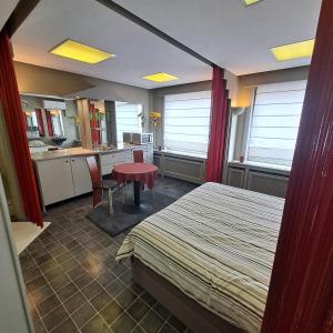 a bedroom with a bed and a table and a kitchen at BeautyD STUDIO double of twin met extra vouwbed centrum Gullegem in Gullegem