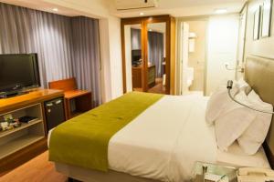 a bedroom with a large bed and a television at Quality Porto Alegre in Porto Alegre