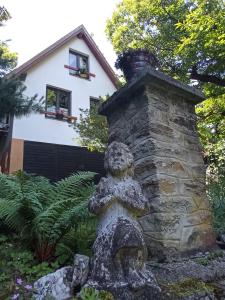 einen Steinkamin mit einer Bärenstatue vor einem Haus in der Unterkunft Pele vendégház in Velem