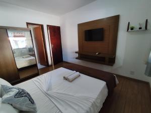 a bedroom with a bed with a tv on the wall at Residencial 7 Mares in Rio das Ostras