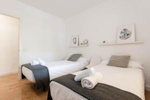 two beds in a room with white walls and wooden floors at Port Apartments in Port d'Alcudia
